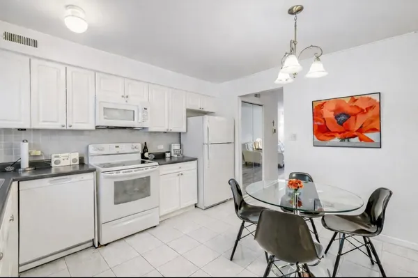 a kitchen with stainless steel appliances granite countertop a stove a refrigerator a dining table and chairs with wooden floor