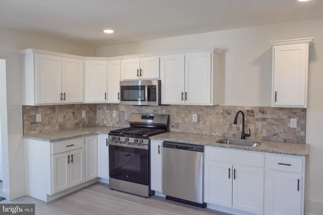 a kitchen with granite countertop white cabinets and stainless steel appliances