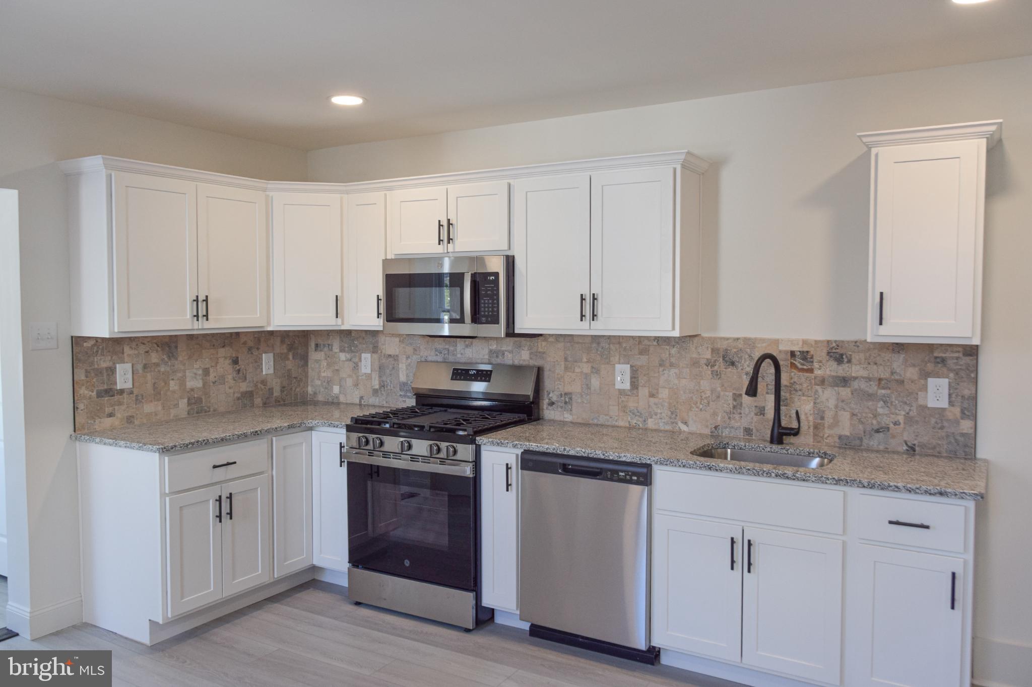 a kitchen with granite countertop white cabinets and stainless steel appliances