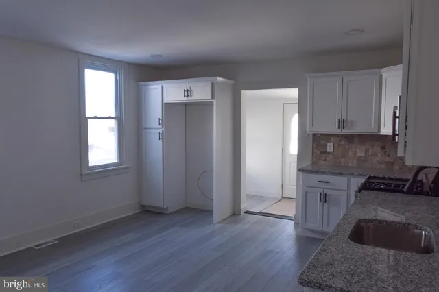 a kitchen with granite countertop white cabinets and wooden floor