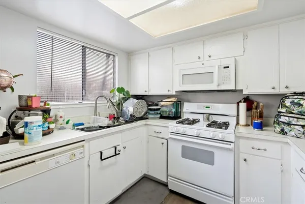 a kitchen with granite countertop white cabinets sink and stainless steel appliances