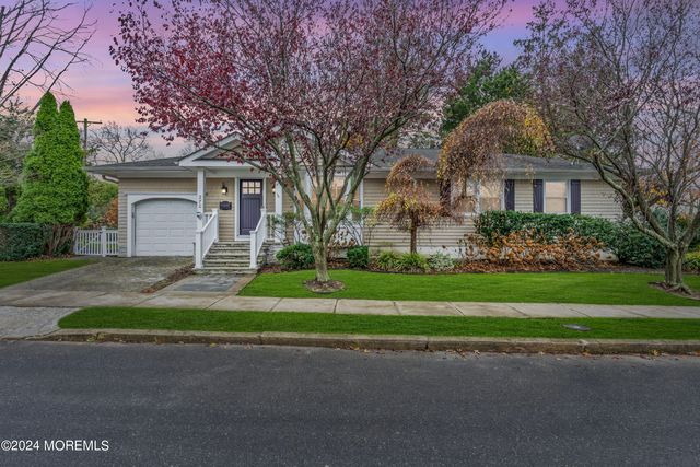 a front view of a house with a garden and trees