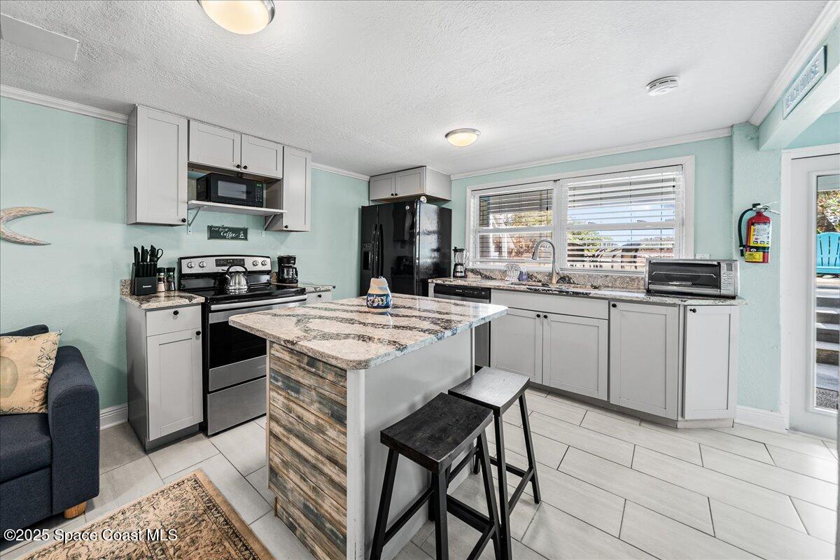 111 South Atlantic Avenue Cocoa Beach, FL 32931 - Photo 20 of 71 a kitchen with a stove a sink a microwave a dining table and chairs