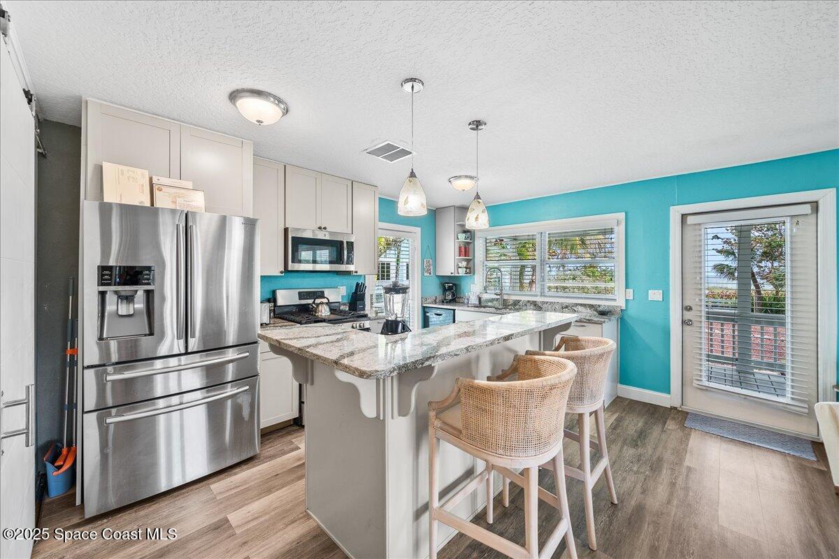 111 South Atlantic Avenue Cocoa Beach, FL 32931 - Photo 42 of 71 a kitchen with stainless steel appliances a dining table chairs refrigerator and stove