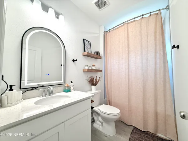 a bathroom with a granite countertop sink a toilet and a mirror
