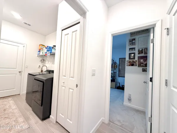 a hallway with white cabinets and refrigerator