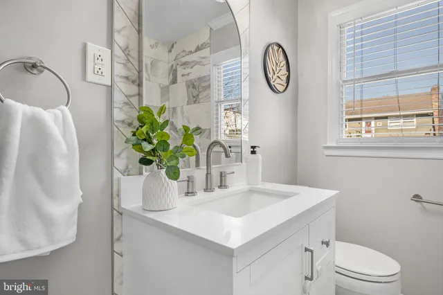 a bathroom with a granite countertop sink a toilet and a mirror