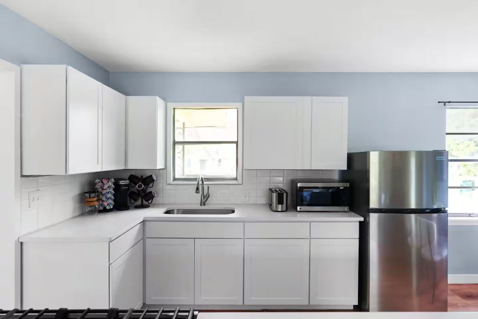 1100 Neans Drive Austin, TX 78758 - Photo 3 of 40 Kitchen with stainless steel appliances, white cabinetry, decorative backsplash, and light stone counters