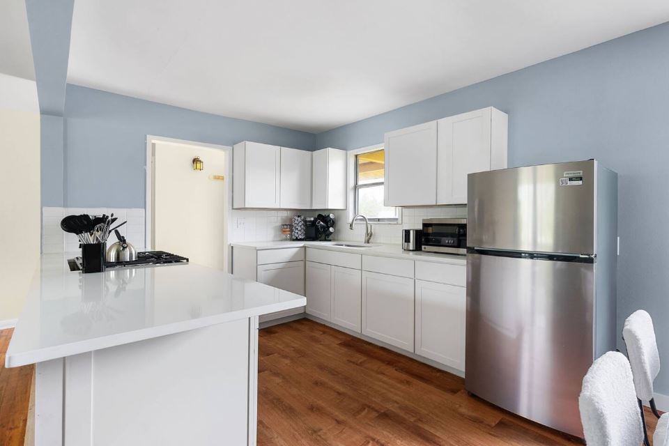 1100 Neans Drive Austin, TX 78758 - Photo 4 of 40 Kitchen featuring stainless steel appliances, dark wood-style flooring, white cabinetry, decorative backsplash, and a peninsula