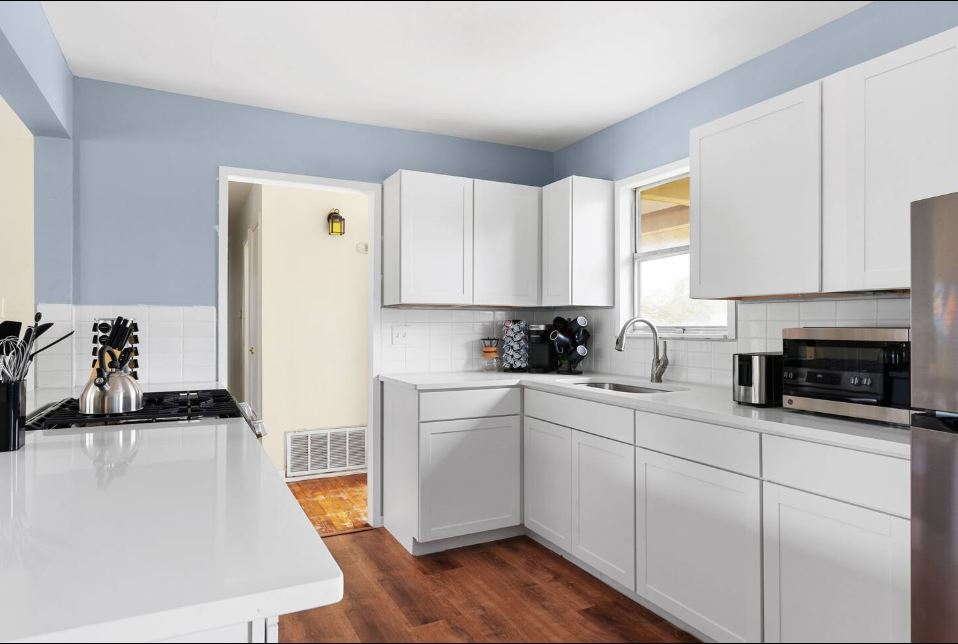 1100 Neans Drive Austin, TX 78758 - Photo 5 of 40 Kitchen with dark wood-style floors, white cabinets, stainless steel appliances, light stone counters, and decorative backsplash