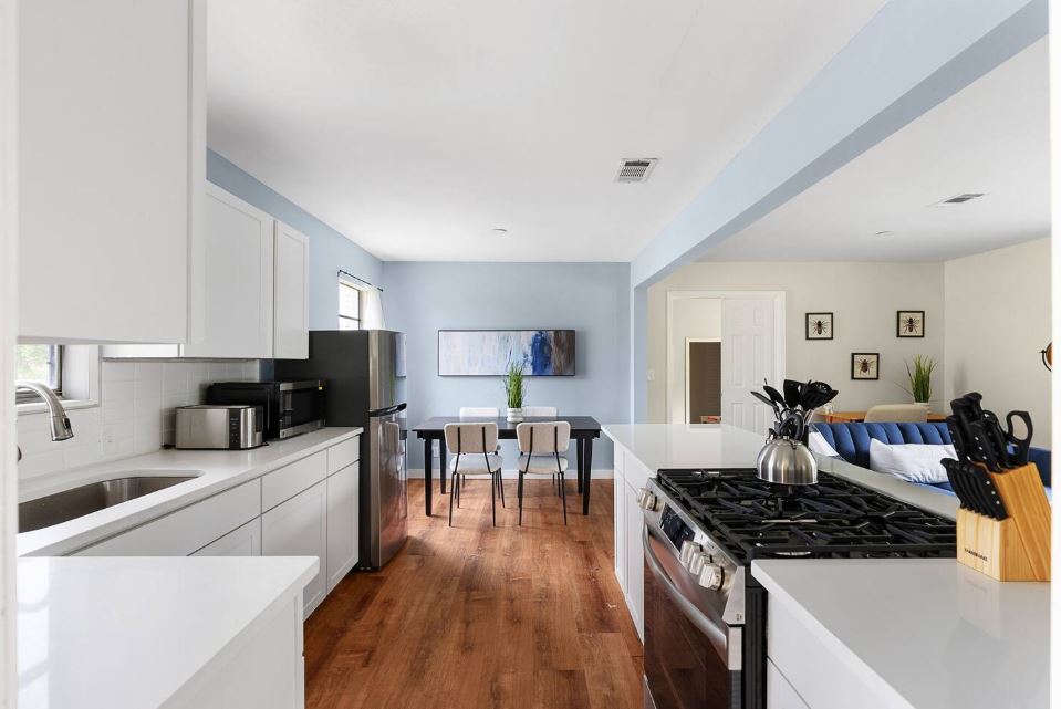 1100 Neans Drive Austin, TX 78758 - Photo 40 of 40 Kitchen with stainless steel appliances, dark wood-type flooring, white cabinets, decorative backsplash, and open floor plan