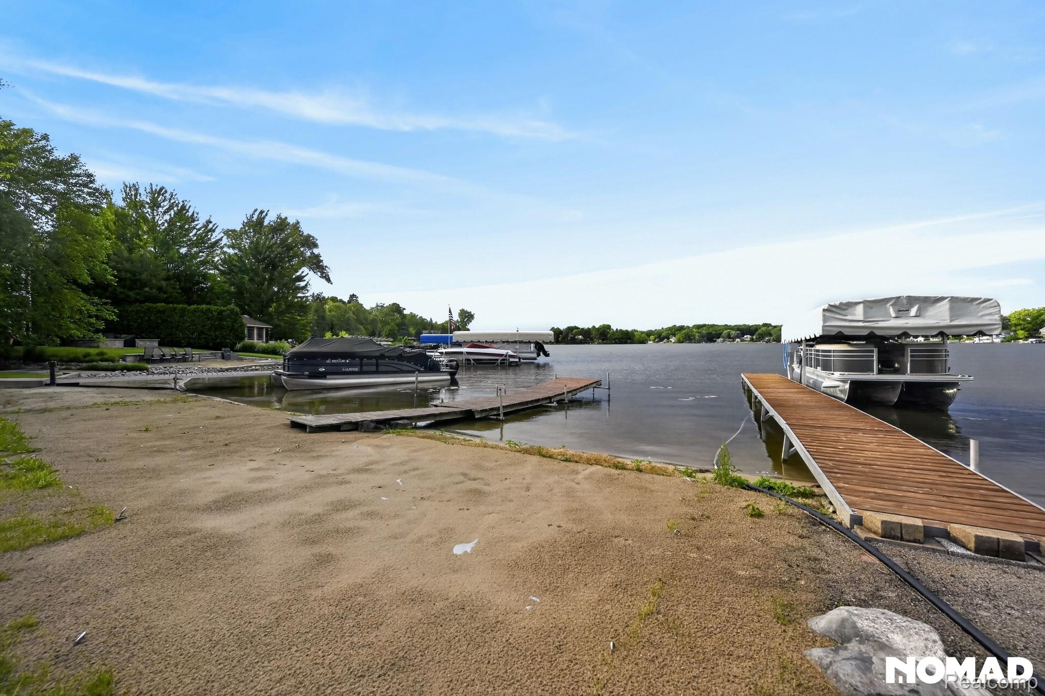 8315 Hilton Road Brighton, MI 48114 - Photo 26 of 26 Waterfront property featuring a sandy beach, private boat docks, and mature trees along the shoreline