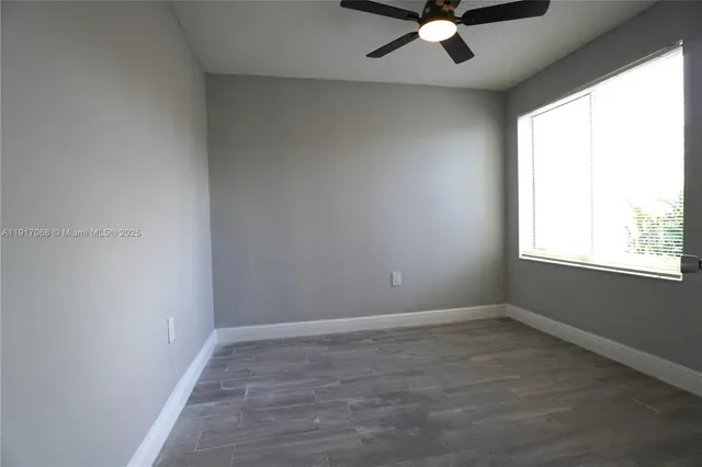 an empty room with a window and a fan