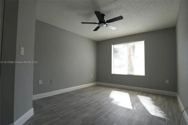 an empty room with wooden floor fan and windows