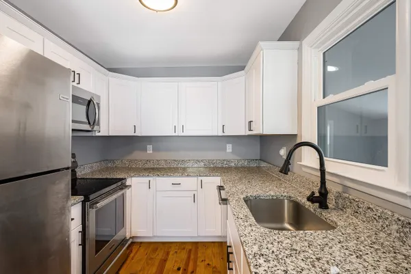 a kitchen with granite countertop a sink a stove and cabinets