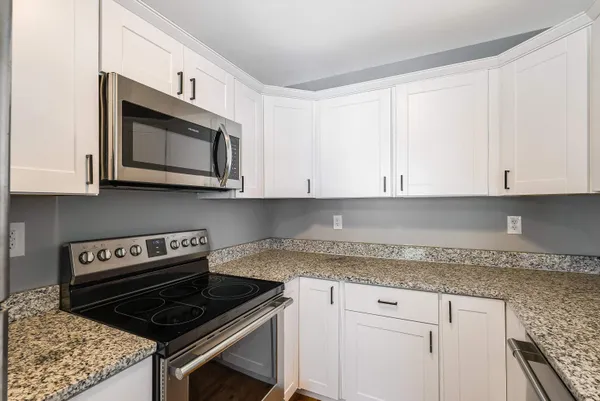 a kitchen with granite countertop white cabinets and a stove top oven