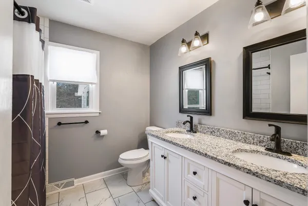 a bathroom with a granite countertop toilet sink and mirror