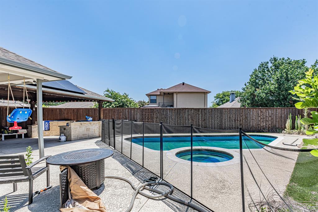 300 Sundance Circle Irving, TX 75063 - Photo 37 of 39 Expansive backyard featuring a fenced swimming pool with an integrated spa, an outdoor kitchen with stone veneer, a covered patio area, and concrete decking