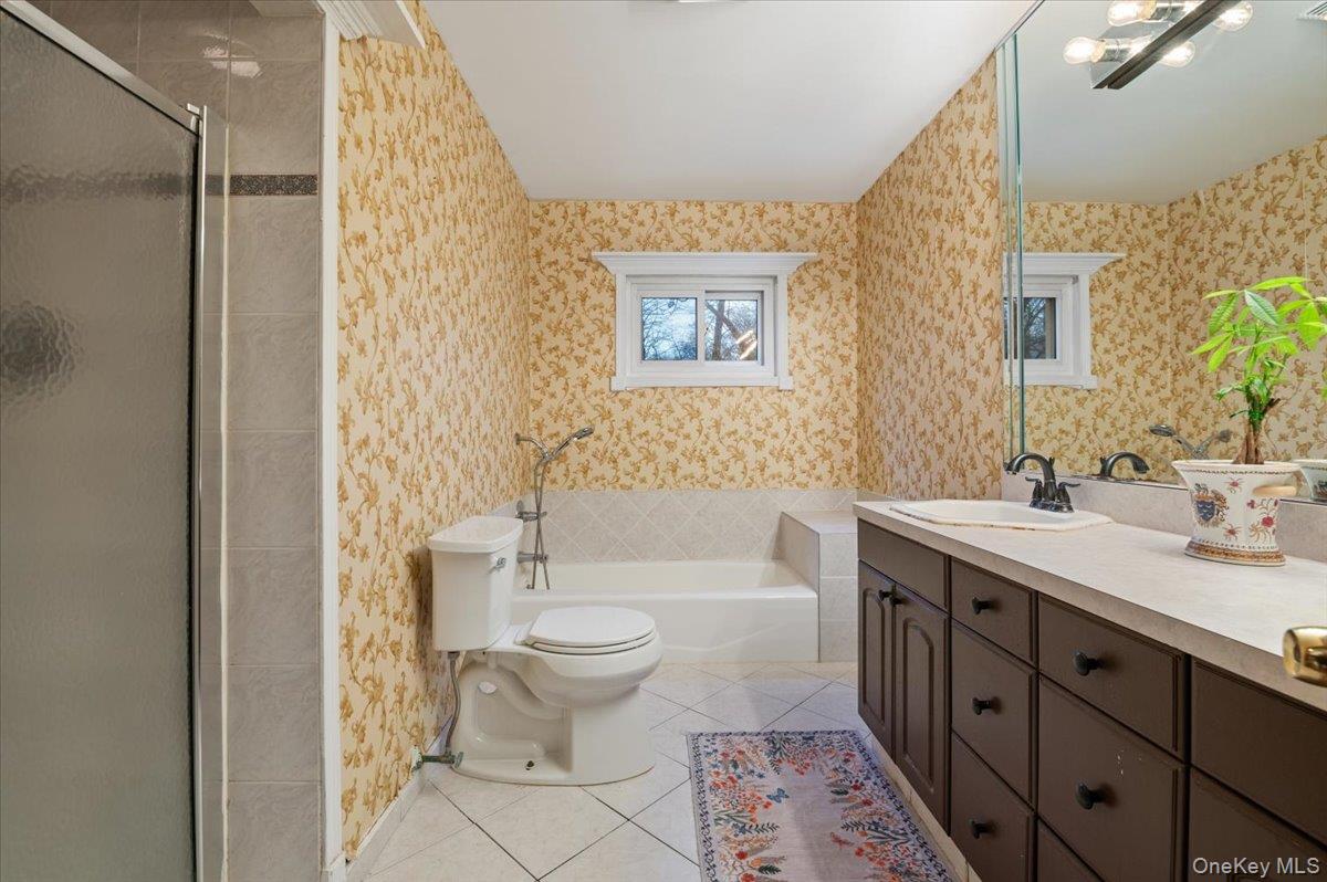 33 Fleets Cove Road Huntington, NY 11743 - Photo 22 of 42 Bathroom featuring wallpapered walls, light tile patterned flooring, a stall shower, vanity, and a garden tub