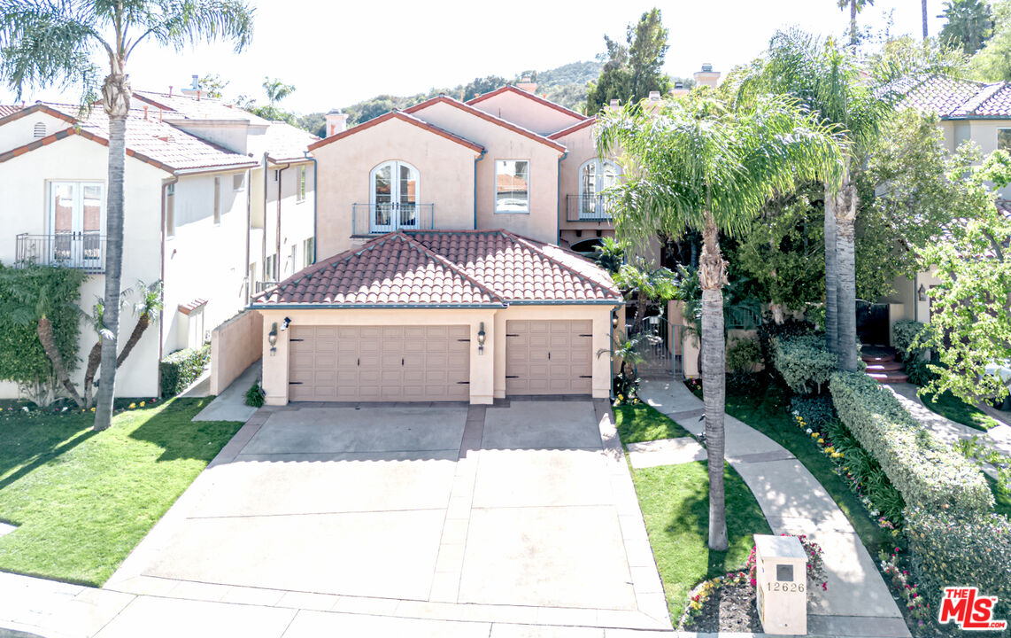 12626 Promontory Road Los Angeles, CA 90049 - Photo 2 of 34 a front view of a house with a garden and trees