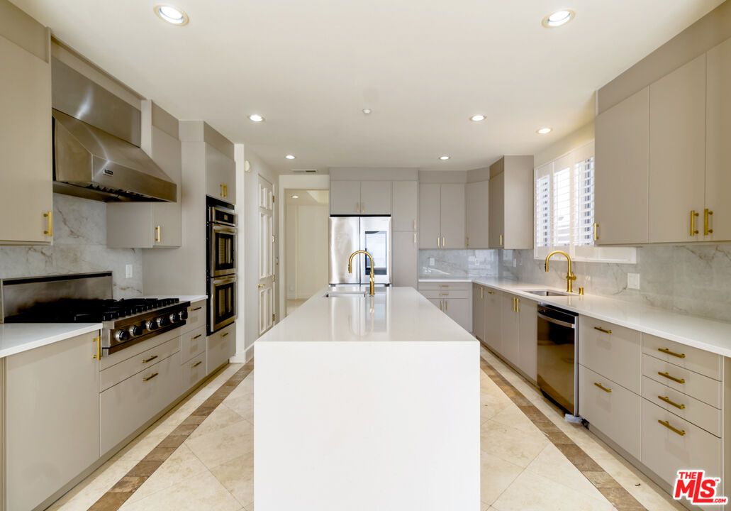 12626 Promontory Road Los Angeles, CA 90049 - Photo 3 of 34 a kitchen with stainless steel appliances kitchen island a sink a stove and a refrigerator