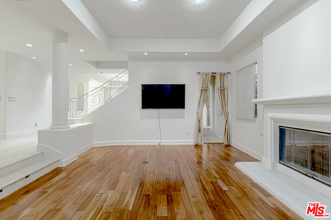 12626 Promontory Road Los Angeles, CA 90049 - Photo 7 of 34 a view of empty room with wooden floor and fireplace