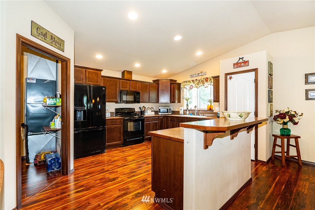 5120 180th Trail Southwest Rochester, WA 98579 - Photo 13 of 32 a kitchen with stainless steel appliances kitchen island granite countertop a refrigerator a stove and a wooden floors