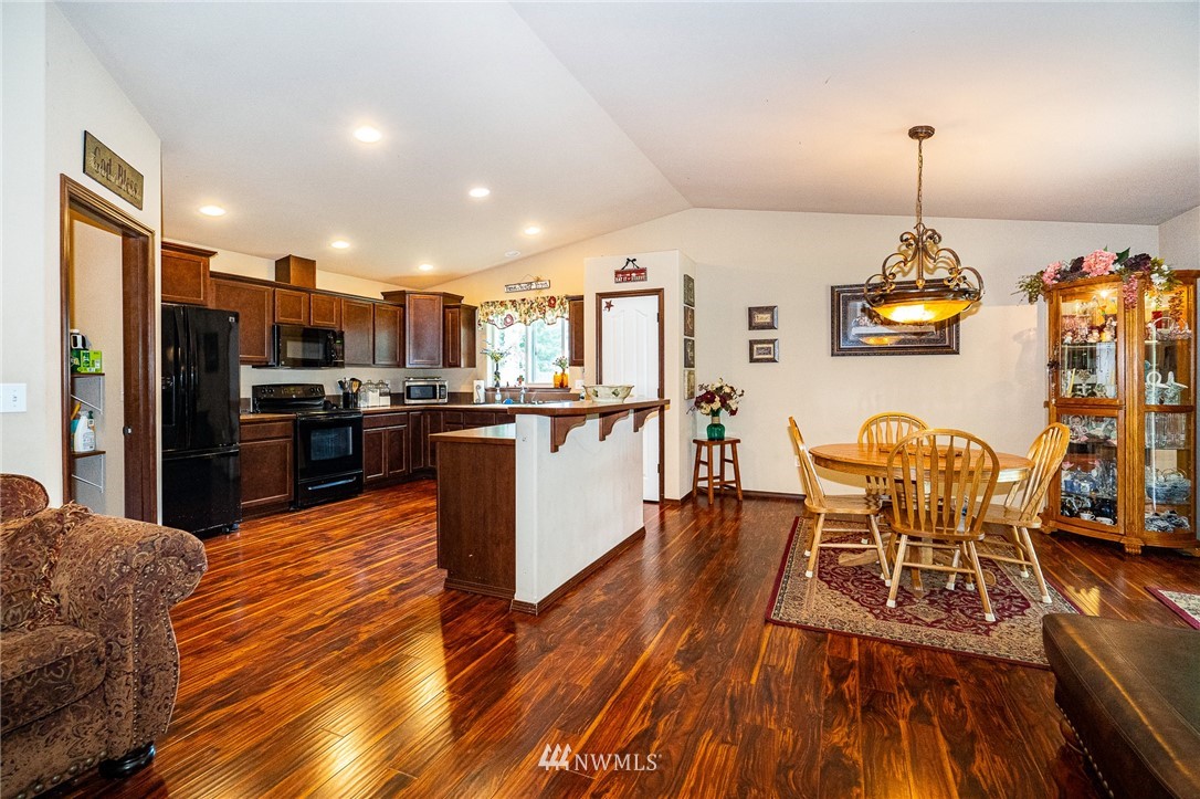 5120 180th Trail Southwest Rochester, WA 98579 - Photo 14 of 32 a kitchen with stainless steel appliances granite countertop a stove top oven a refrigerator a dining table and chairs with wooden floor