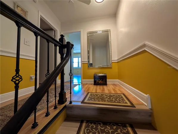 a view of a hallway with wooden floor and stairs