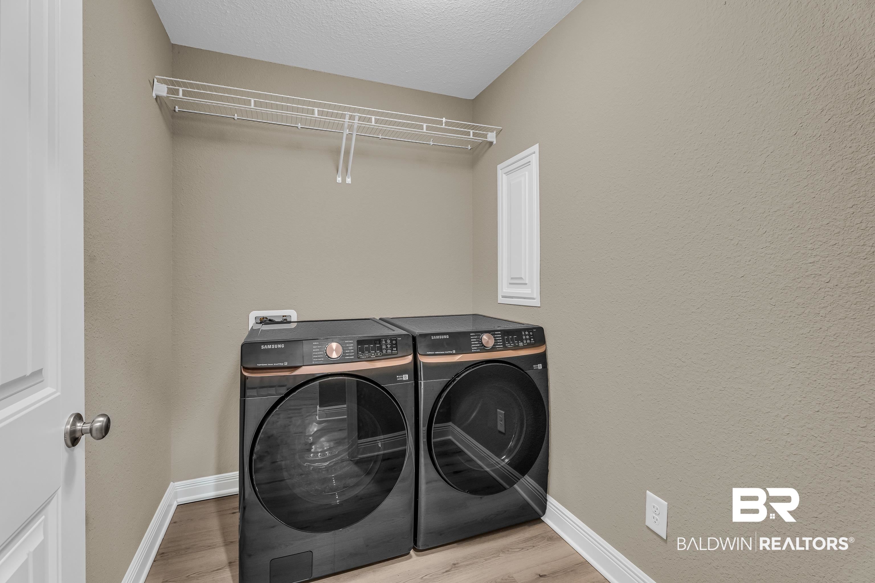 9206 Greenleaf Drive Daphne, AL 36527 - Photo 22 of 32 Laundry area featuring wood finished floors, washer and clothes dryer, a textured ceiling, and a textured wall