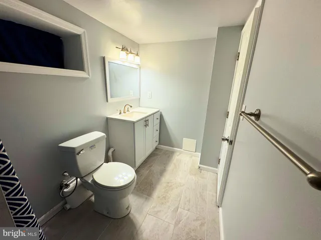 a white toilet sitting next to a bathroom sink and a mirror