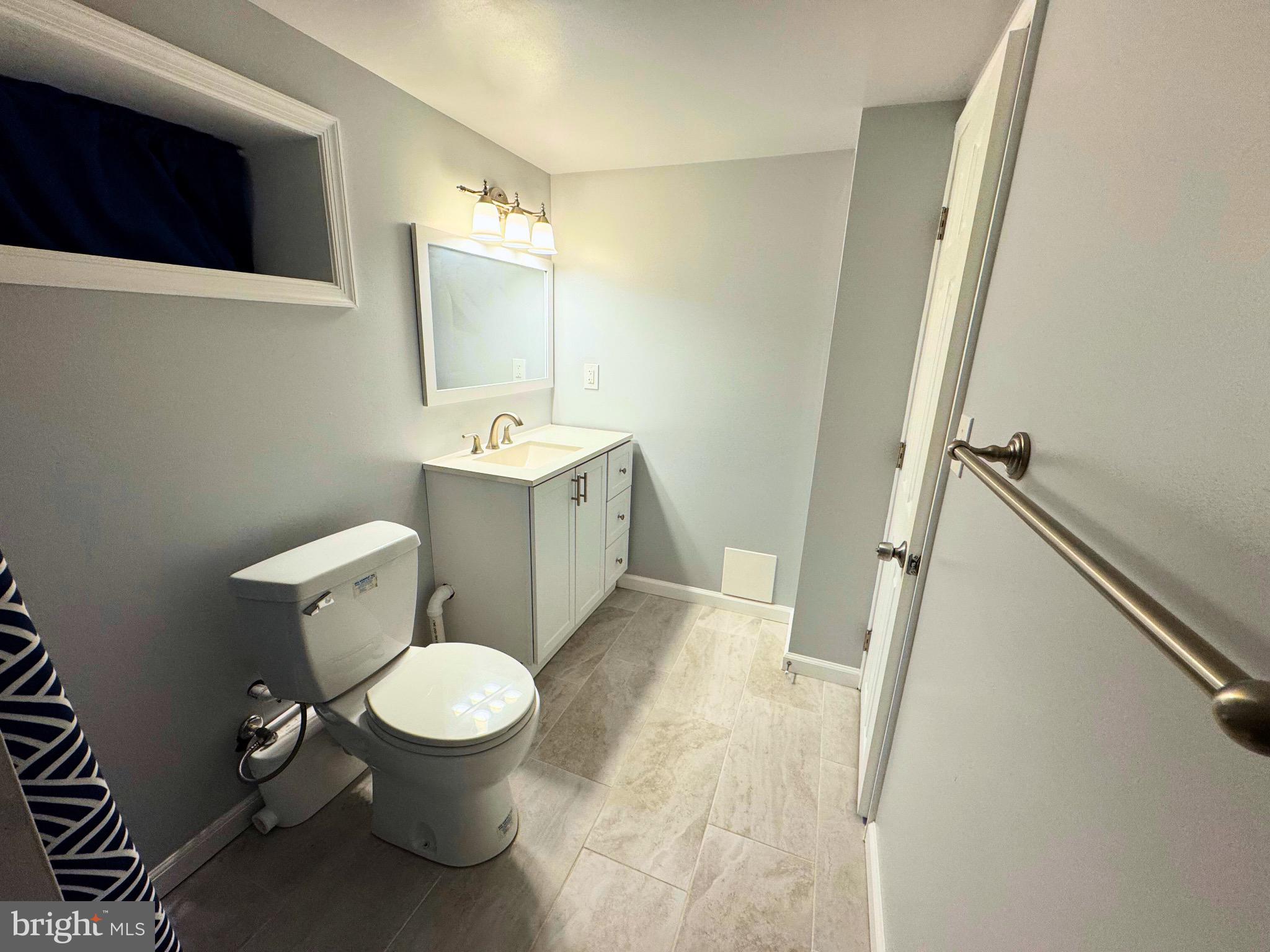 2909 Duncan Lane Parkville, MD 21234 - Photo 15 of 20 a white toilet sitting next to a bathroom sink and a mirror