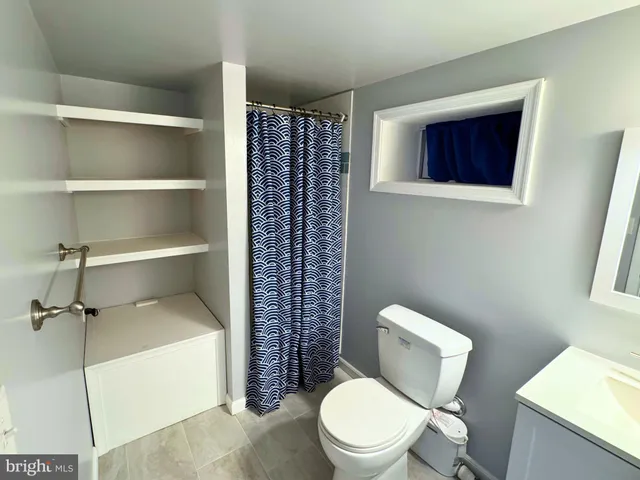 a white toilet sitting next to a bathroom sink and vanity