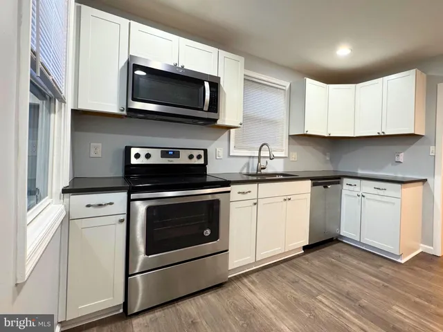 a kitchen with stainless steel appliances granite countertop a sink a stove top oven and white cabinets
