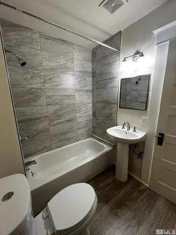 a bathroom with a sink a toilet a mirror and shower