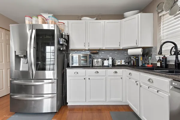 a kitchen with stainless steel appliances granite countertop a refrigerator and white cabinets
