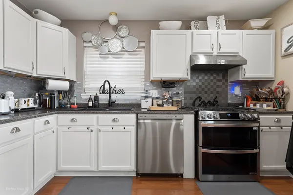 a kitchen with stainless steel appliances granite countertop a sink a stove and cabinets