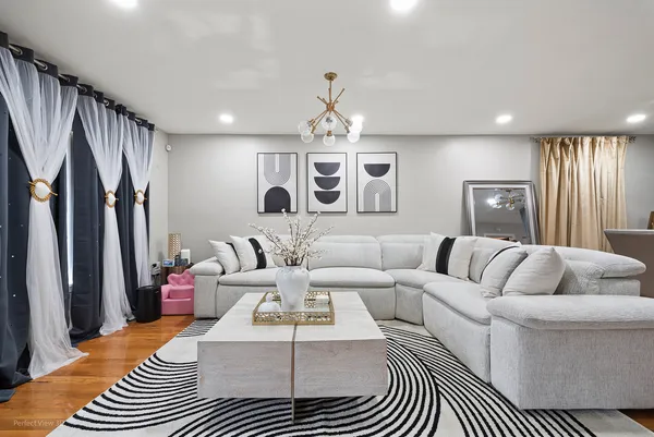 a living room with furniture a large window and a chandelier