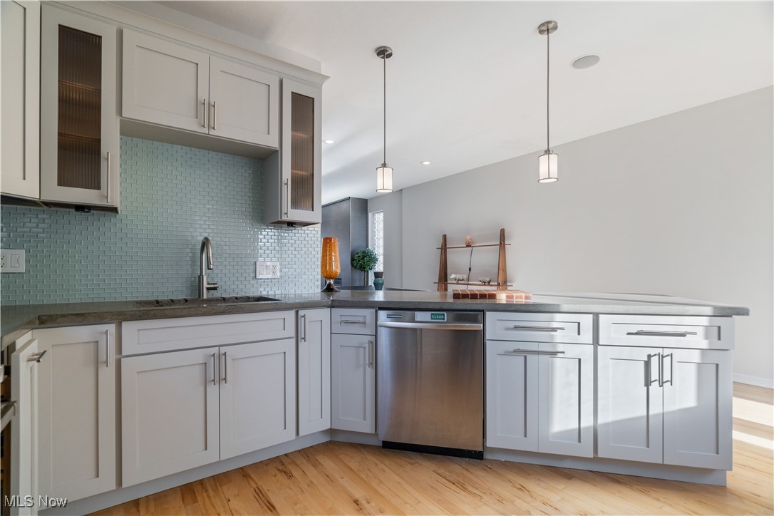 711 University Road Cleveland, OH 44113 - Photo 14 of 36 Kitchen with sink, hanging light fixtures, backsplash, stainless steel dishwasher, and light wood-type flooring