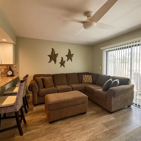 a living room with furniture a ceiling fan and a window