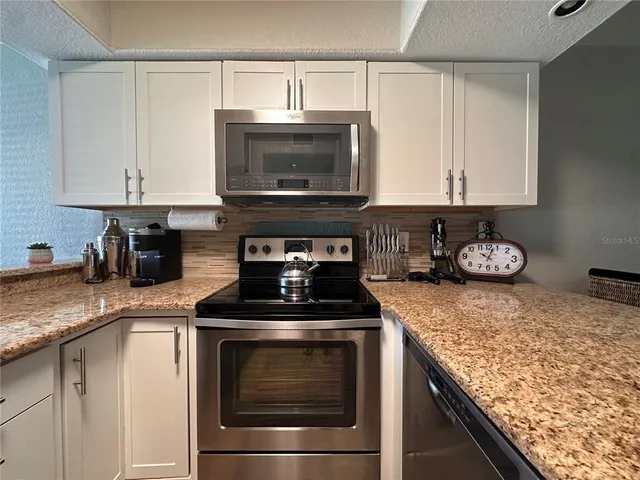 a kitchen with granite countertop a stove and a microwave
