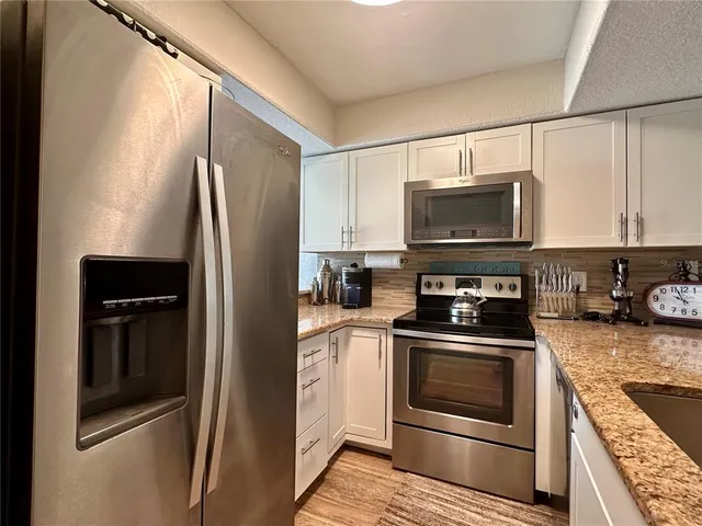 a kitchen with stainless steel appliances granite countertop a refrigerator stove and microwave