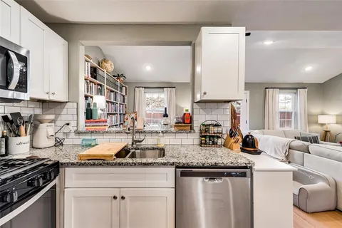a kitchen with granite countertop a stove and white cabinets