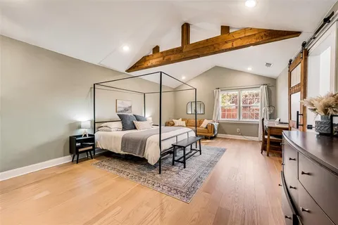 a spacious bedroom with a bed and wooden floor