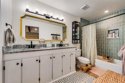a bathroom with a granite countertop sink a toilet a mirror a vanity and shower