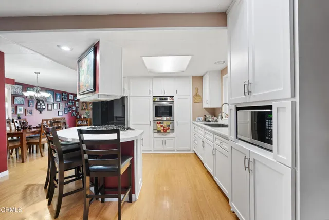 a kitchen with stainless steel appliances kitchen island granite countertop a table chairs in it and a wooden floors