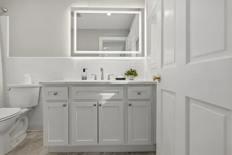 a bathroom with a sink a toilet and a mirror