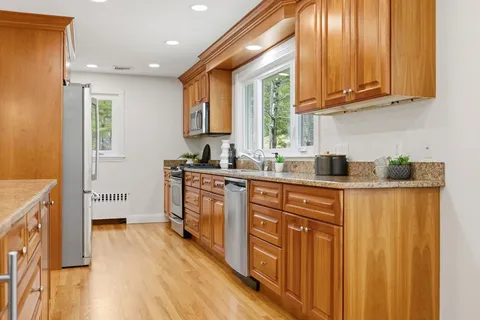 a kitchen with stainless steel appliances granite countertop a sink a stove cabinets and wooden floor