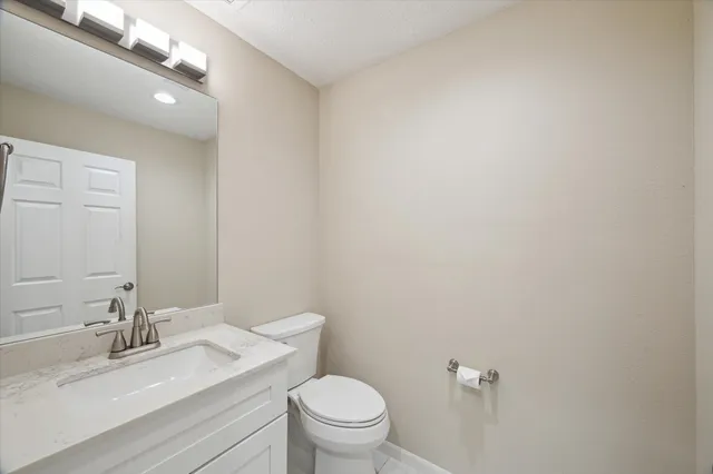 a bathroom with a granite countertop sink a toilet and a mirror