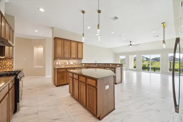 a kitchen with kitchen island granite countertop a stove and a sink